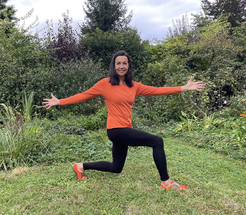 Christine Hector zeigt eine Ausfallschritt-Übung im Garten
